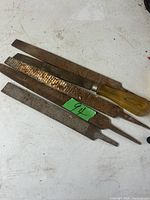 Three metal files of different types and sizes on a white surface with some dirt and rust visible.