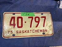 Photo of a 1975 Saskatchewan vehicle license plate, featuring embossed red numbers '40-797' and letters on a white background with signs of wear.