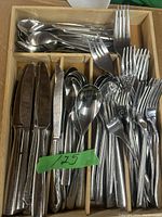 Tray of cutlery including knives, forks, tablespoons, and teaspoons arranged in a divided wooden tray.
