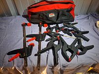 Photo showing all clamps (2 bar clamps, 6 spring clamps) laid out with the JOBMATE carry bag behind.