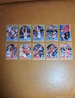 Front view of 10 basketball cards featuring players in action or portrait, arranged in two rows of five on a brown surface.