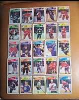 Top side of 25 hockey cards showing images of players from various teams in different colored uniforms with name banners.