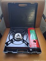 Cookstove inside black carrying case, showing the stove burner and red fuel compartment