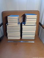 Photo of 39 stacked vintage hardcover books with blue covers from Yale Shakespeare Library on a brown chair, two stacks of varying heights with a ruler at the front for scale.