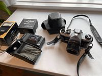 Asahi Pentax Spotmatic camera with attached Super-Takumar lens, leather case, Sekonic light meter, and KeyStone 16mm viewer box displayed on white surface.