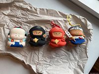 Photo of all four ninja and monk figurines on crumpled brown paper showing front view and colors.