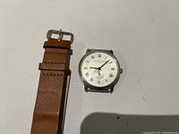 Watch head detached from strap, showing overall case and strap ends on white background