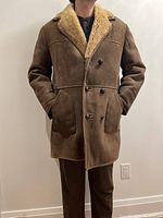 Front view of vintage shearling jacket worn by model, showing brown suede exterior with plush wool collar and double-breasted button closure.