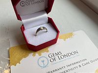 Ring in red Gems of London box with warranty and care guide partially visible.