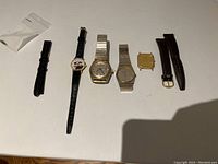 All five watches and four straps laid out in a row showing details of each.