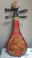 Front view of Chinese pipa lute showing detailed dragon and floral hand painting with red background and gold accents.