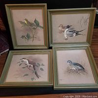 Four framed bird prints arranged for sale; greenish-gold wooden frames, images of birds in naturalistic settings, signed and dated by Fenwick Lansdowne.