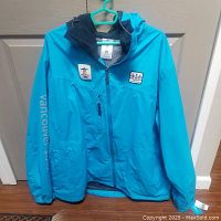 Full front view of turquoise jacket with hood and Vancouver 2010 text down sleeve.