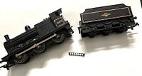 Black Hornby Tri-ang R251 steam locomotive No. 43775 and tender separated, showing details and small detached ladder accessory.
