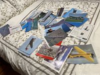 Image showing a large variety of aircraft photos and information sheets spread out on a bed, showcasing the variety and quantity of the collection.