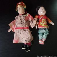 Two vintage Chinese opera puppets laid on black background, showing front side details of costumes and painted faces.
