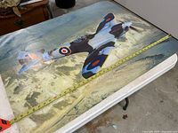 Photo showing large poster lying flat on table with tape measure indicating length around 39 inches.