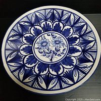 Top view of vintage hand painted blue and white ceramic decorative wall plate with floral design.
