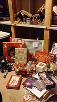 Photo shows assorted Christmas decorations on the floor including cards, gift bags, ornaments, and string lights.