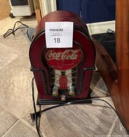 Front and side view of the Coca Cola stained glass look AM/FM radio showing shape, color, power cord, and control knobs.
