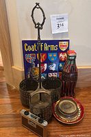 Vintage Coat of Arms activity book positioned behind antique metal bottle cady and vintage Coca-Cola tin bottle with small dish and decorative plate.