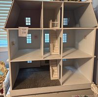 Front view showing three floors, eight rooms, staircase and three carpeted rooms inside the dollhouse.