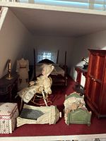 Dollhouse bedroom furniture including bed, mannequin, cradle, ottoman, armoire, and gramophone.