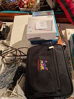 View showing ViewSonic projector case with embroidered logo and ASUS ZenDrive DVD writer box on top along with assorted cables.