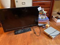 Photo of LG 32 inch TV model 32CS460UC without remote, Diamond Vision DVD player, stack of books on hardwood floor