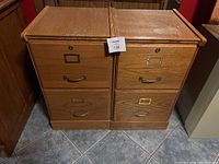 Front view of two wooden two-drawer filing cabinets showing drawer handles and label holders