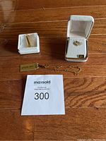 Group shot of 14K gold bracelet and two charms on wooden floor