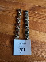 Photo of two JZ Mexico sterling silver bracelets with red and grey stone inlays side by side on wooden floor