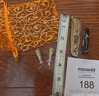 Photo showing all items together with measuring tape for scale, decorative orange mesh pouch, two fish pendants, folding pocket utensil, and small black key ring utensil.