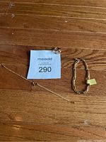 Ring, two bracelets laid on wood floor marked with lot tag