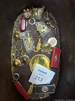 Photo of various gold tone key chains and lockets displayed on a dark surface