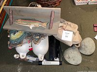 Photo showing two white boat bumpers, fishing net or buoy, wooden fish decor sign and outdoor vest