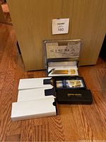 Overall lot showing multiple pen and pencil sets, some still in packaging, arranged on floor.