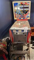 Full view of pinball machine including backbox art and playfield under glass