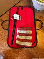 Complete lot showing the sai and folded flag inside a red carrying bag lined with soft fabric.