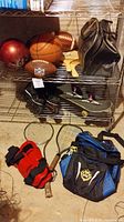 Photo showing basketball, footballs, rollerblades, skateboard, tennis racket, and duffle bag.