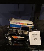 Pair of toy cars on black reflective surface, showing Corvette Gasser in front and VW Drag Bus behind