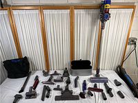 Full layout of Dyson V8 Animal vacuum and all its attachments spread out on a white surface, including the vacuum body, wand, motorized head, various brushes and tools.