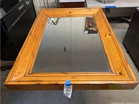 Full view of extra large rectangular mirror lying flat showing the wood frame and beveled edge mirror glass.