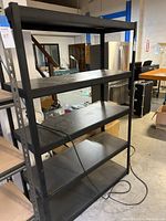 Five shelf metal and wood storage rack positioned in a warehouse environment, showing full shelving unit