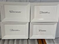 Four white rectangular plates arranged in a 2x2 grid showing various Oscar Wilde quotes in black text.