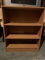 Front view of the wooden bookcase showing the three open shelves and closed base shelf