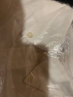 Close-up photo showing the button-down collar and buttons of the white shirt.