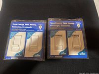 Front view of two 2-pack blister packages of Leviton slide dimmer light switches on black background showing white switches with sliders and packaging text Save Energy Save Money.