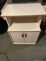 Front view of white microwave cart with minor markings on the solid top surface.