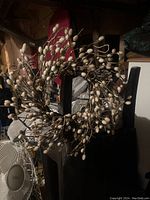 Image of pussywillow wreath hanging on a chair showing the circular arrangement and natural brown twigs with soft light beige buds.